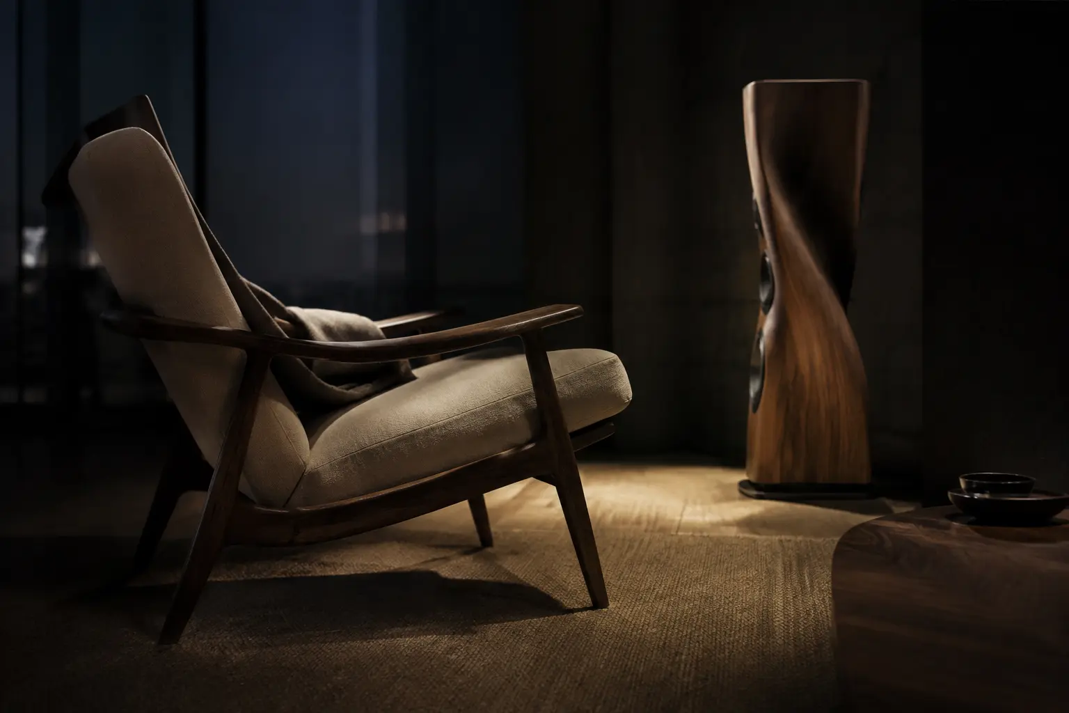 A sculptural listening chair and speaker in a quiet dark room